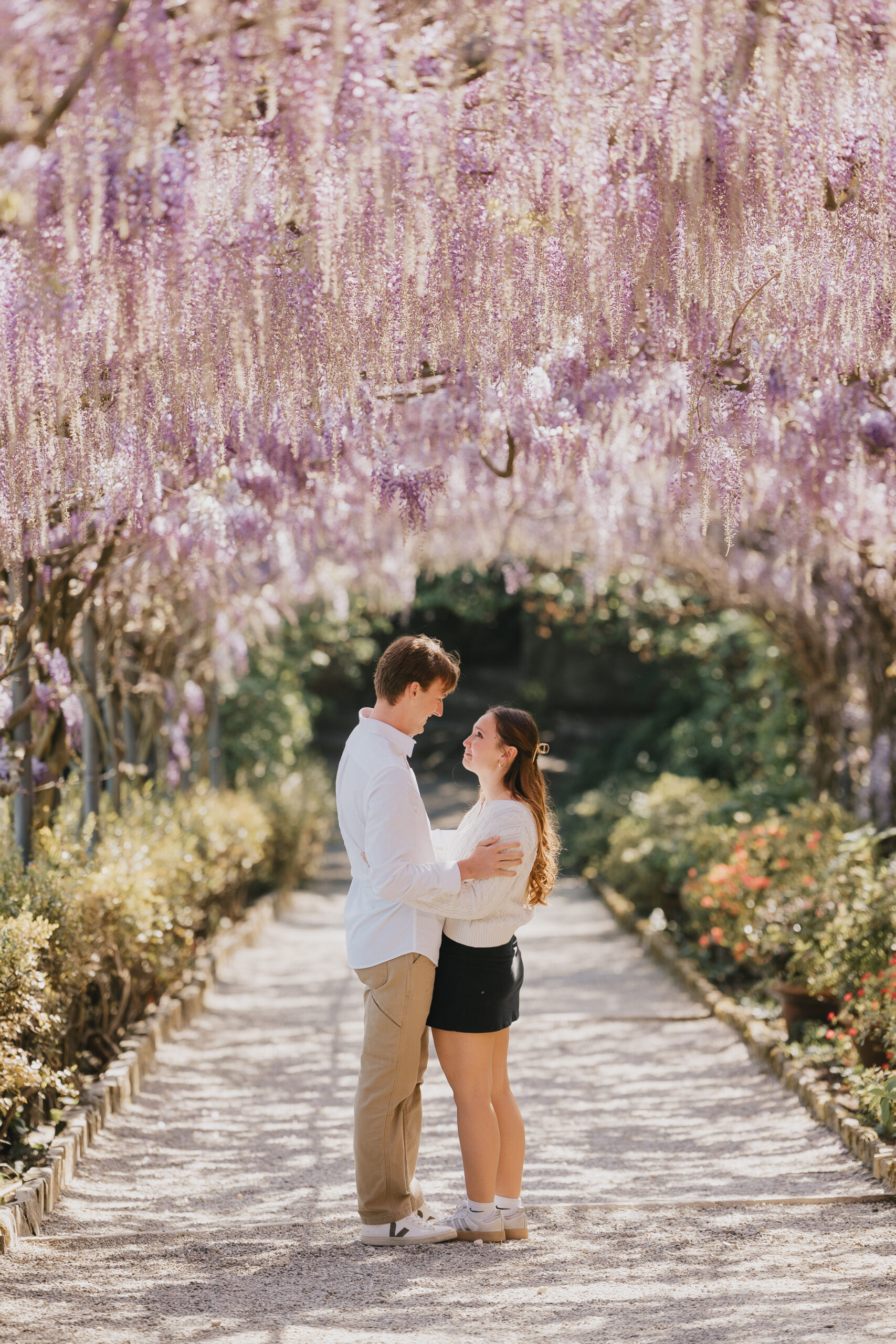 Proposal photoshoot under the wisteria pergola at Villa Bardini, Florence: couple embracing on the garden path
