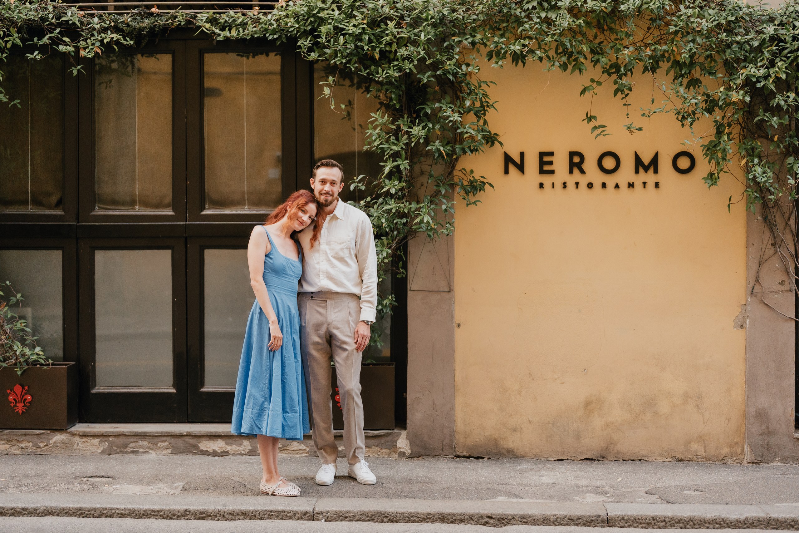 Couple in a blue dress and linen shirt leaning on a doorway in a Florence street