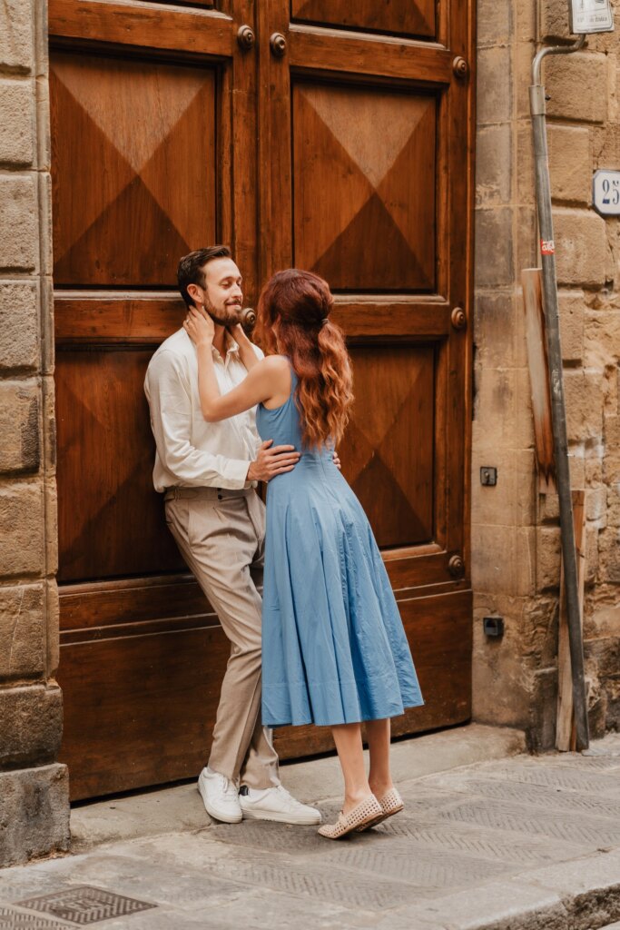 Couple embracing against a large wooden door in a Florence street