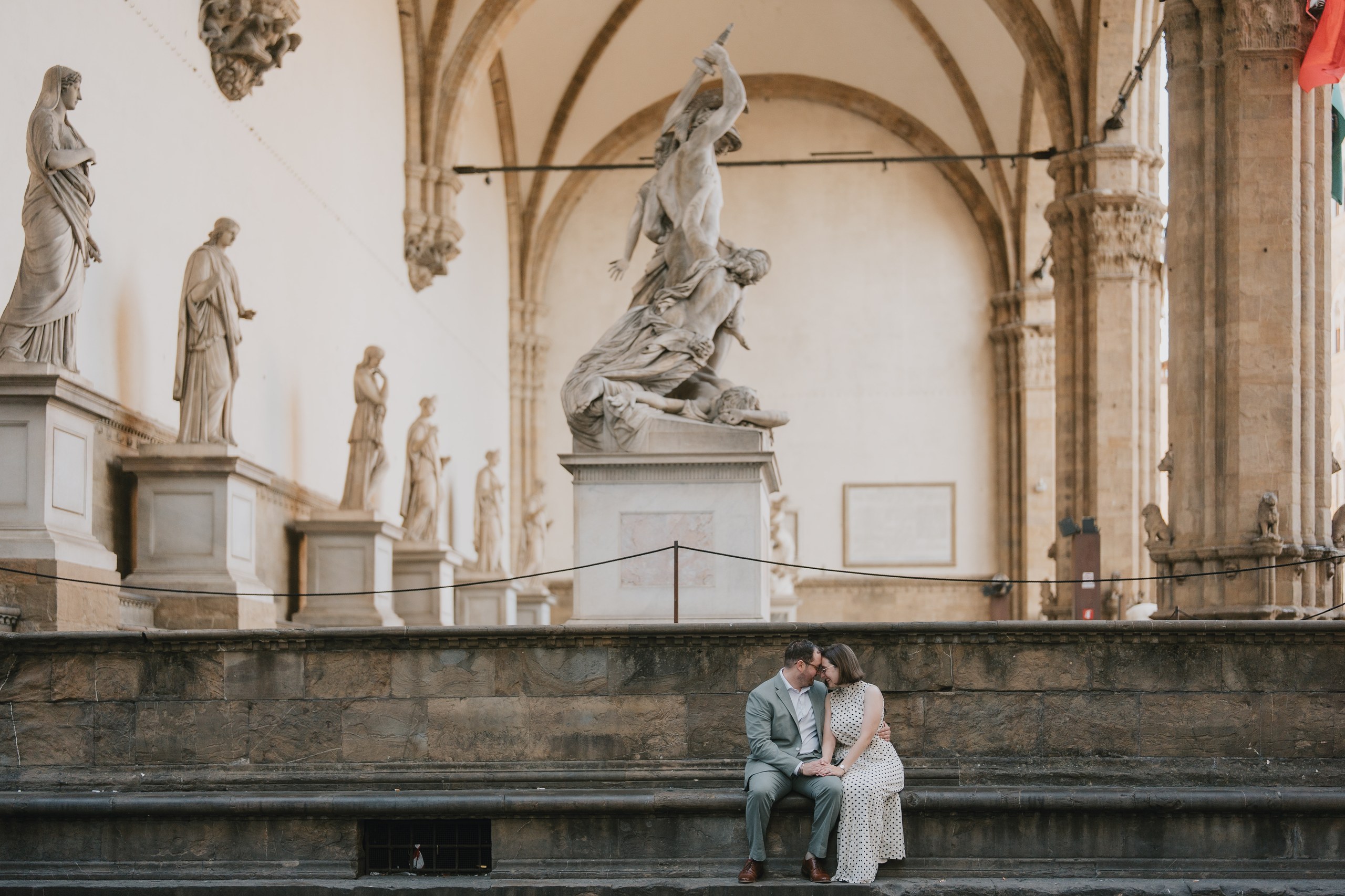 Couple sitting on the steps of the Loggia dei Lanzi among the statues, Florence