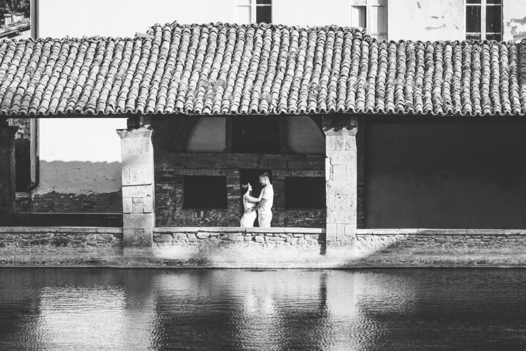 Expecting couple embracing under the stone loggia of the thermal pool in Bagno Vignoni