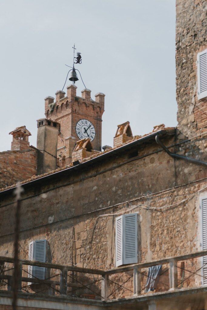The clock tower of the town hall in Pienza above the stone houses of the historic centre