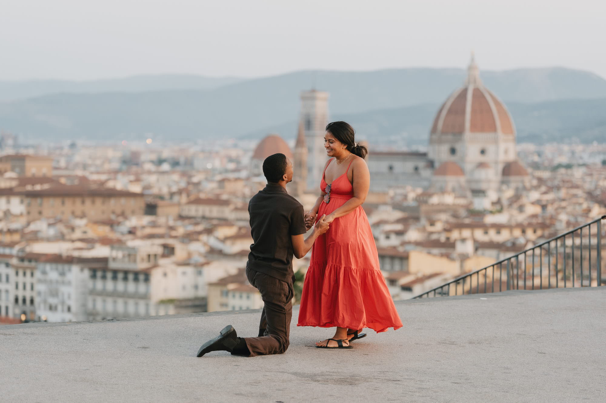 Man on one knee proposing at Piazzale Michelangelo in Florence, with the Duomo and the city rooftops behind them and the terrace empty