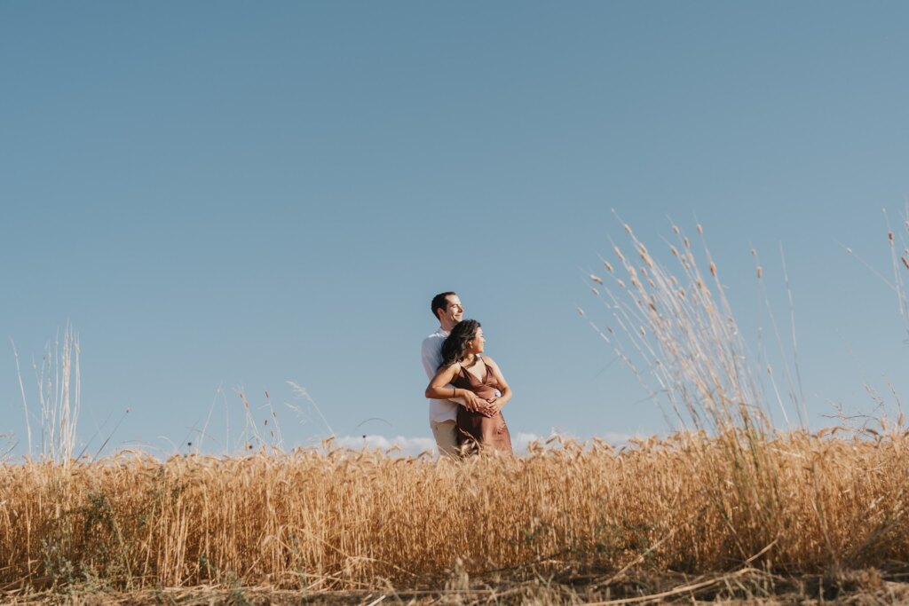 Val d'Orcia proposal: the couple embracing in a golden wheat field under a clear blue sky