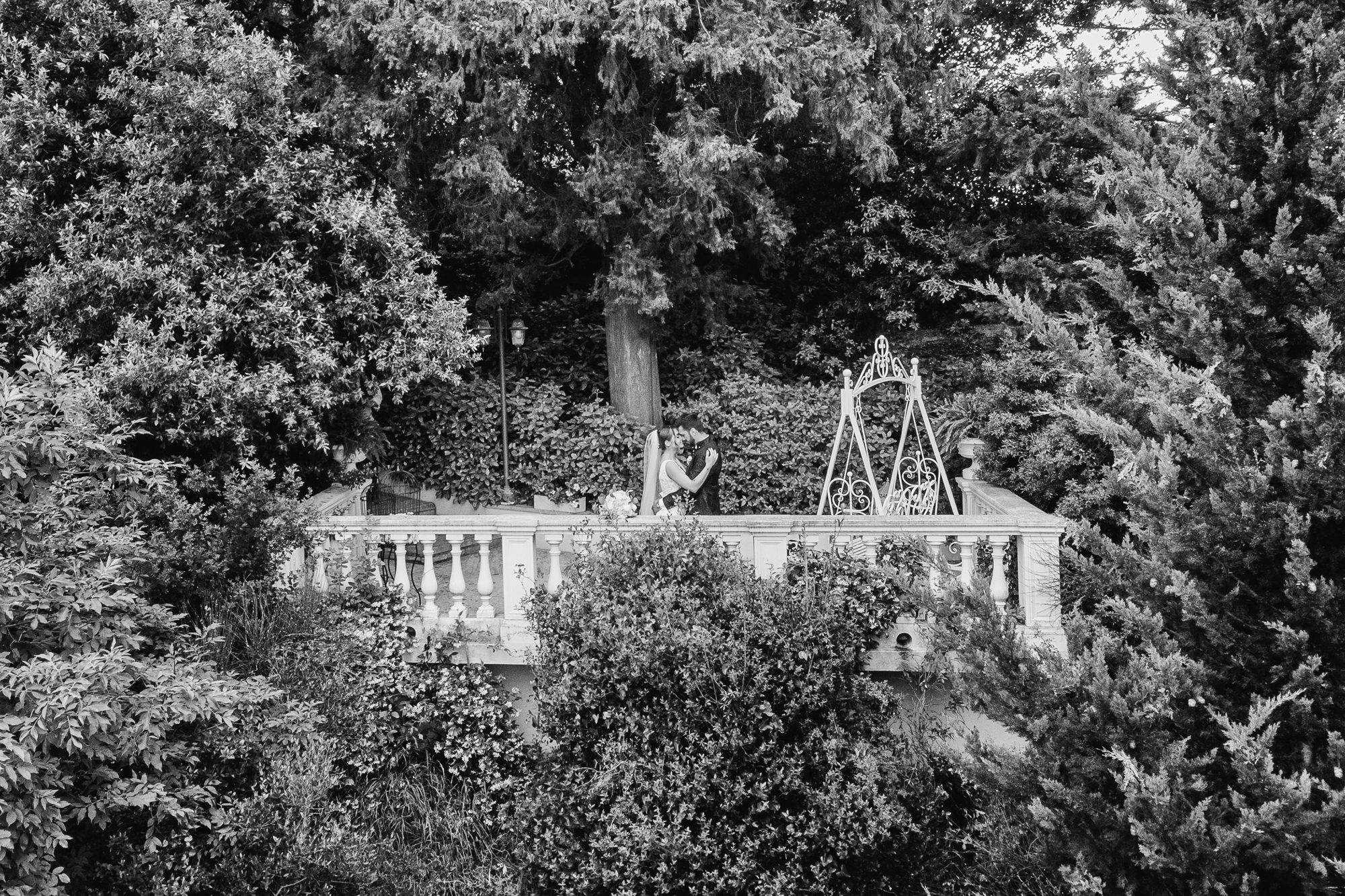 Black and white aerial view of a bride and groom on the balustraded terrace of Villa Il Petriccio, near Florence, surrounded by trees