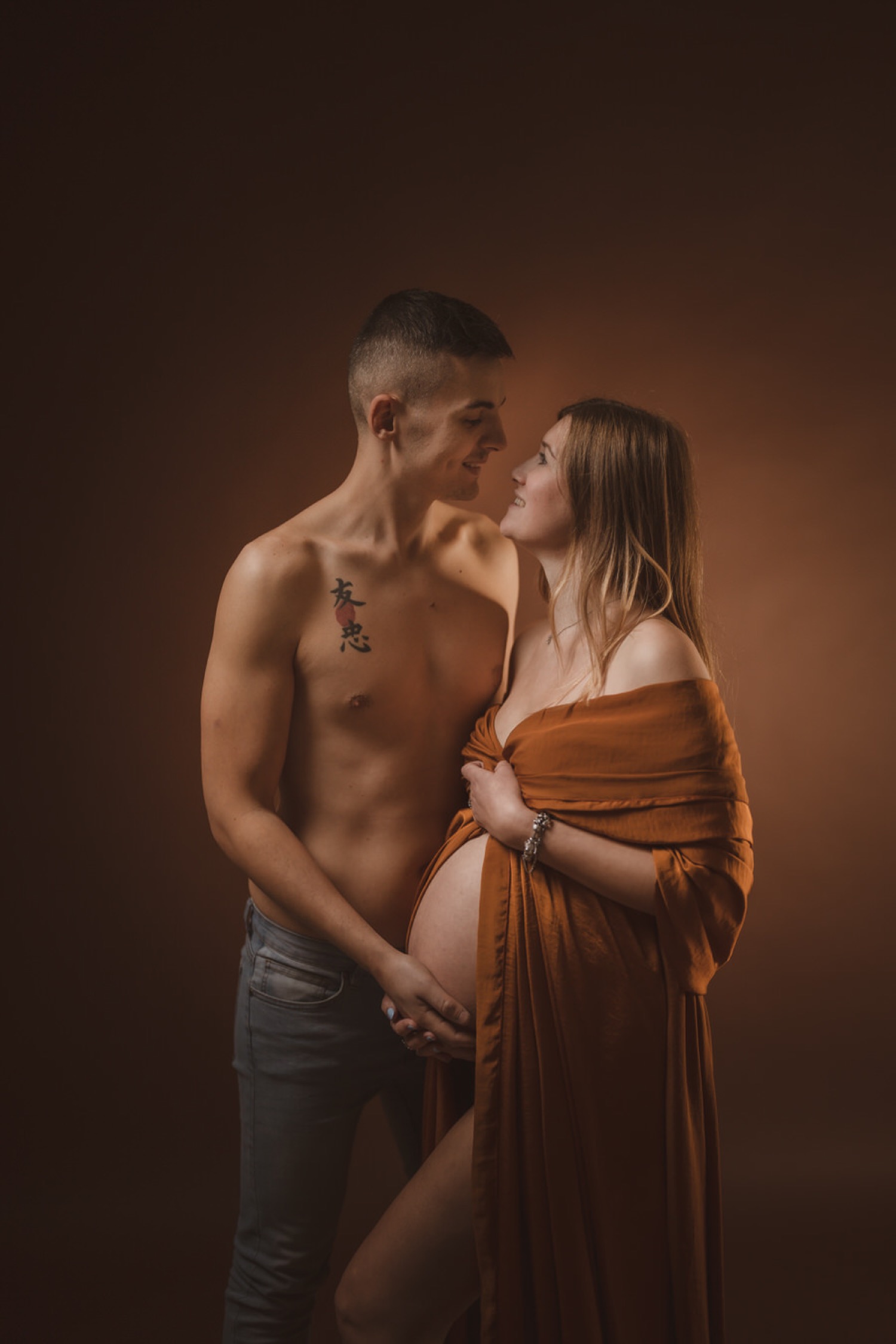 Coppia in attesa in studio, lei avvolta nel telo, lui a torso nudo