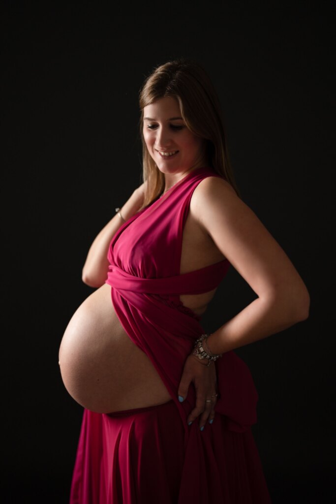 Futura mamma in abito fucsia su fondo nero