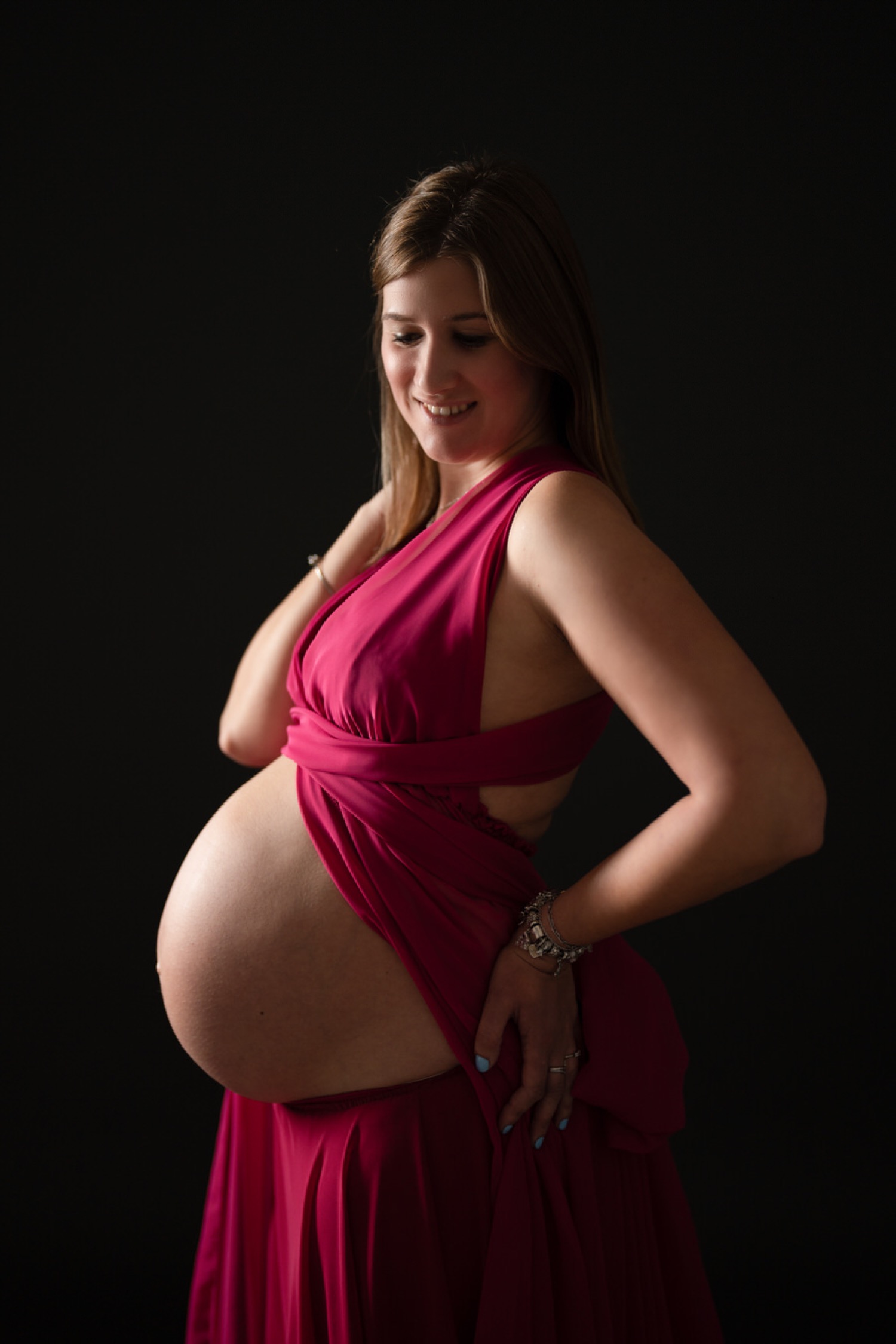 Futura mamma in abito fucsia su fondo nero