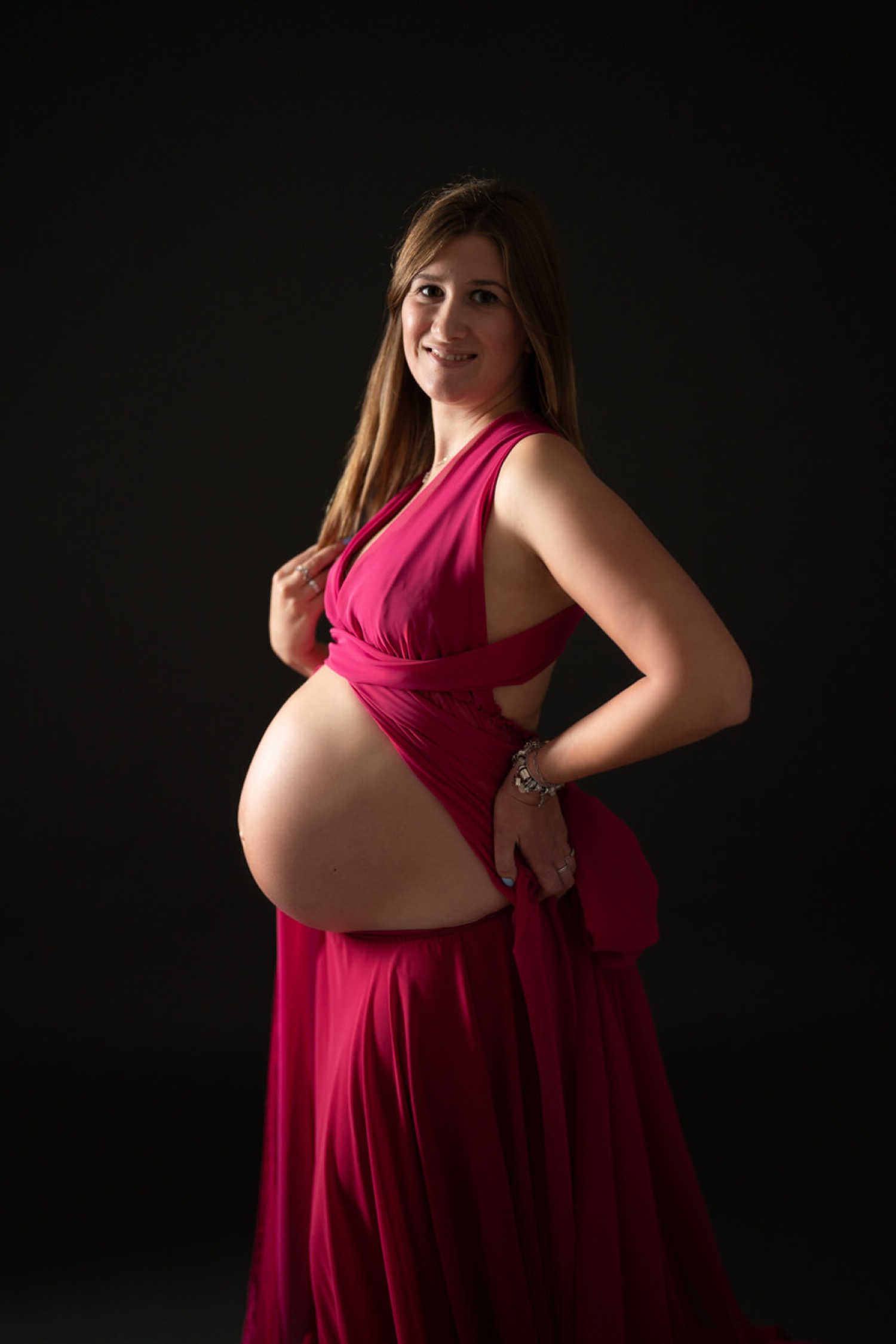 Ritratto di tre quarti in abito fucsia, mani sul fianco