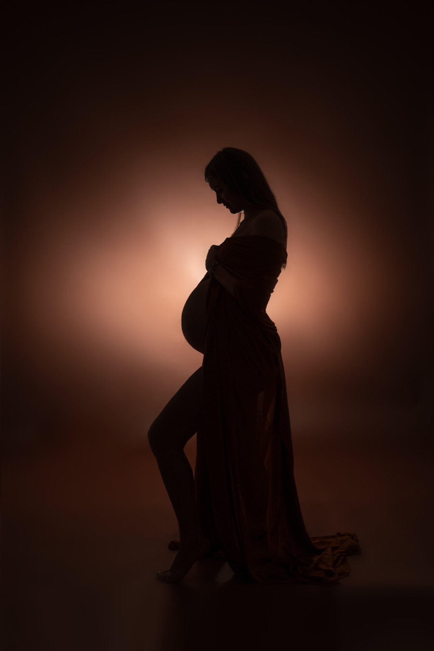 Silhouette del pancione in controluce con abito di tulle rosso