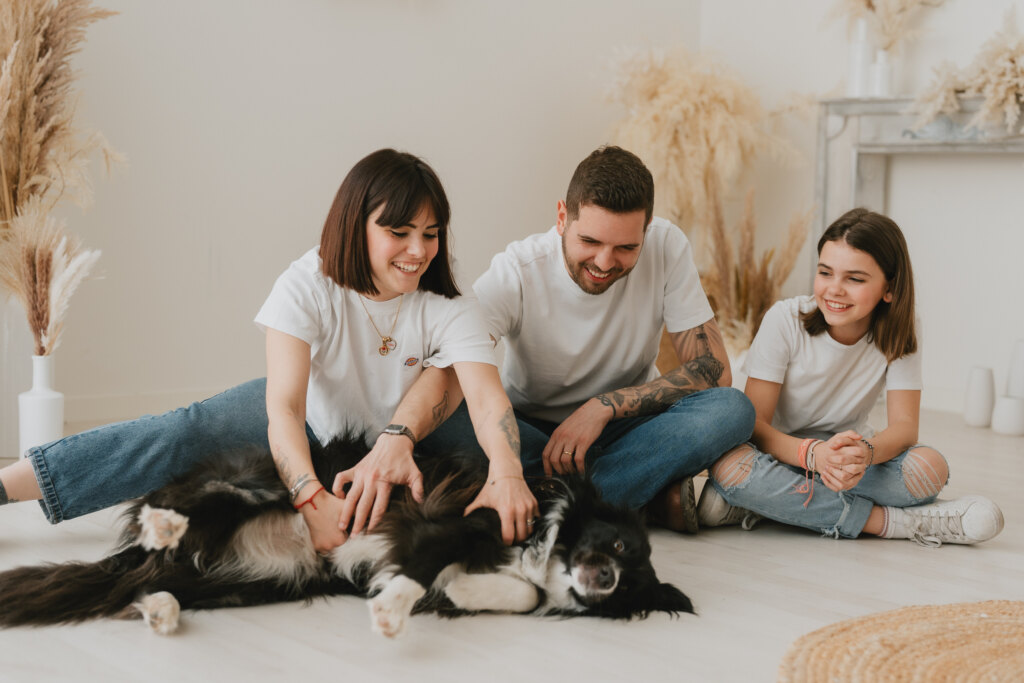Genitori e figlia seduti a terra che giocano con il loro border collie durante un servizio di famiglia nel nostro studio vicino a Firenze