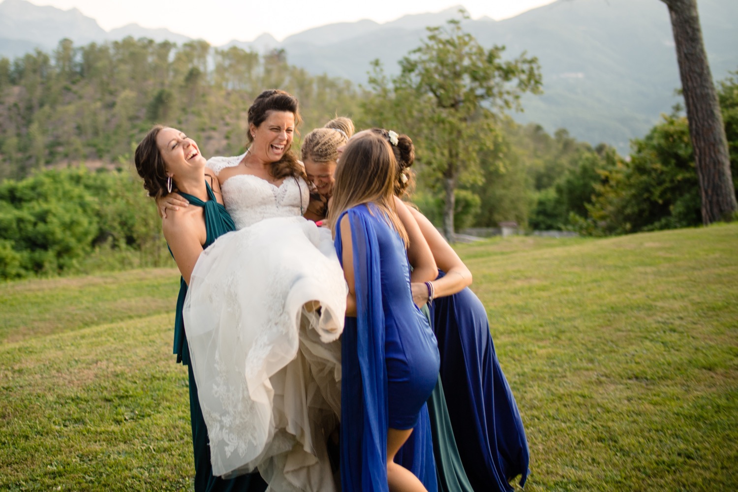 Le amiche abbracciano la sposa nel prato
