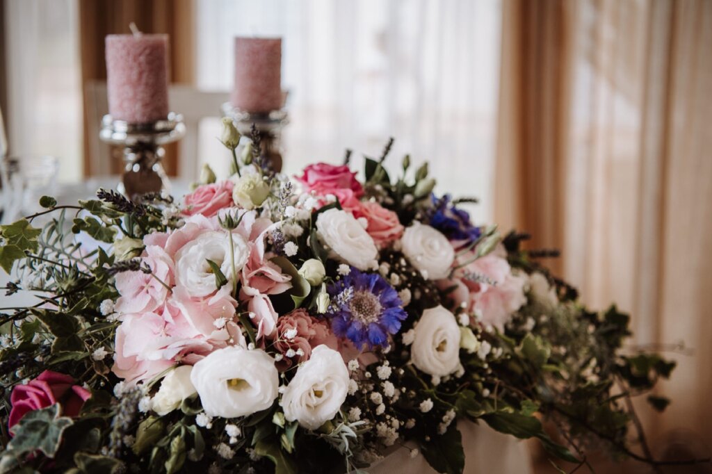 Centrotavola con fiori rosa, bianchi e blu e candele rosa