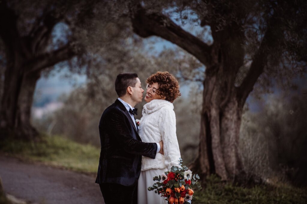 Matrimonio invernale: abbraccio degli sposi sotto un ulivo