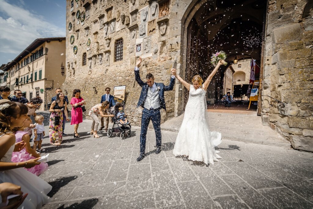La sposa alza il bouquet tra gli invitati in piazza