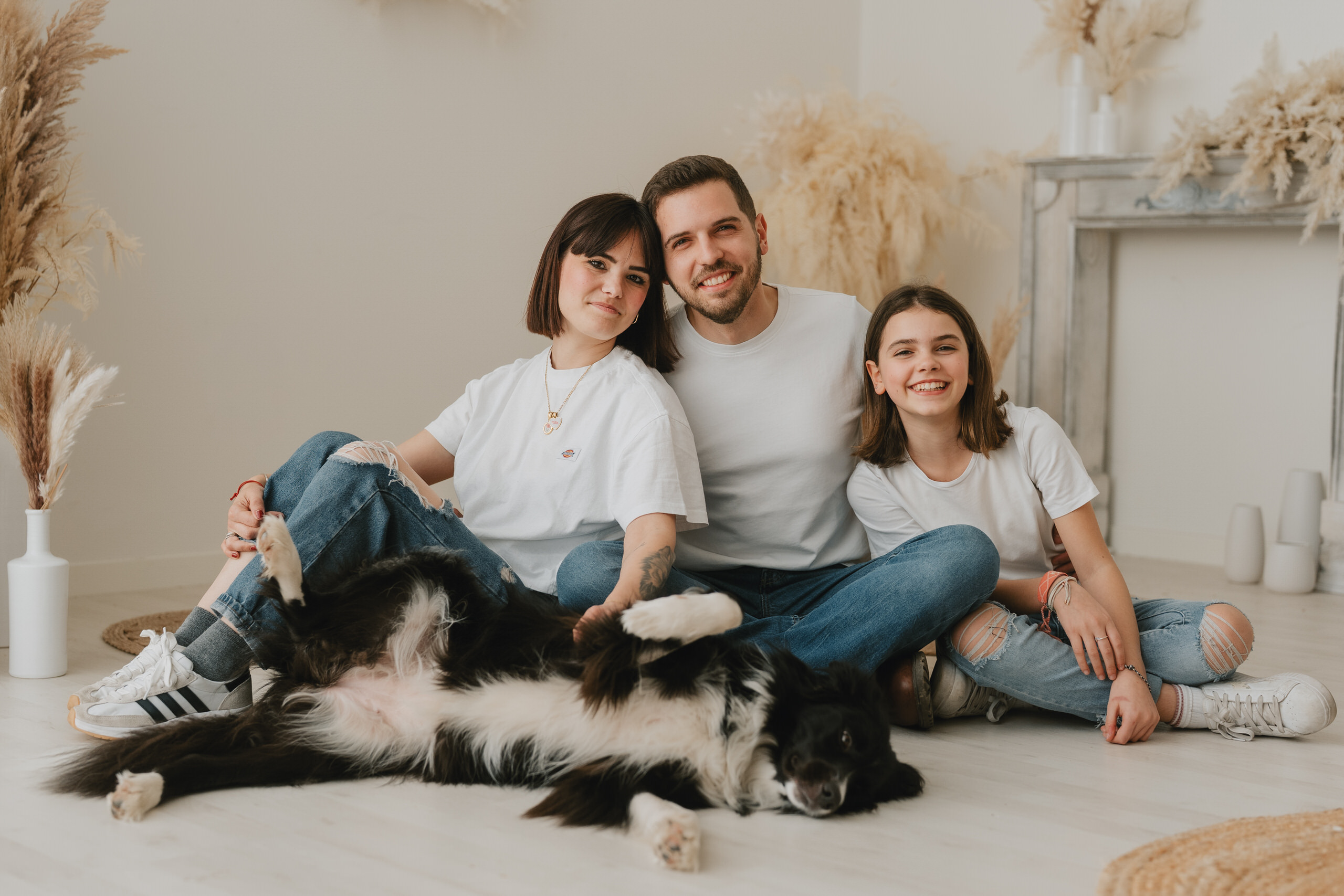 Genitori e figlia sorridenti seduti vicini con il loro border collie sdraiato davanti, nel nostro studio vicino a Firenze