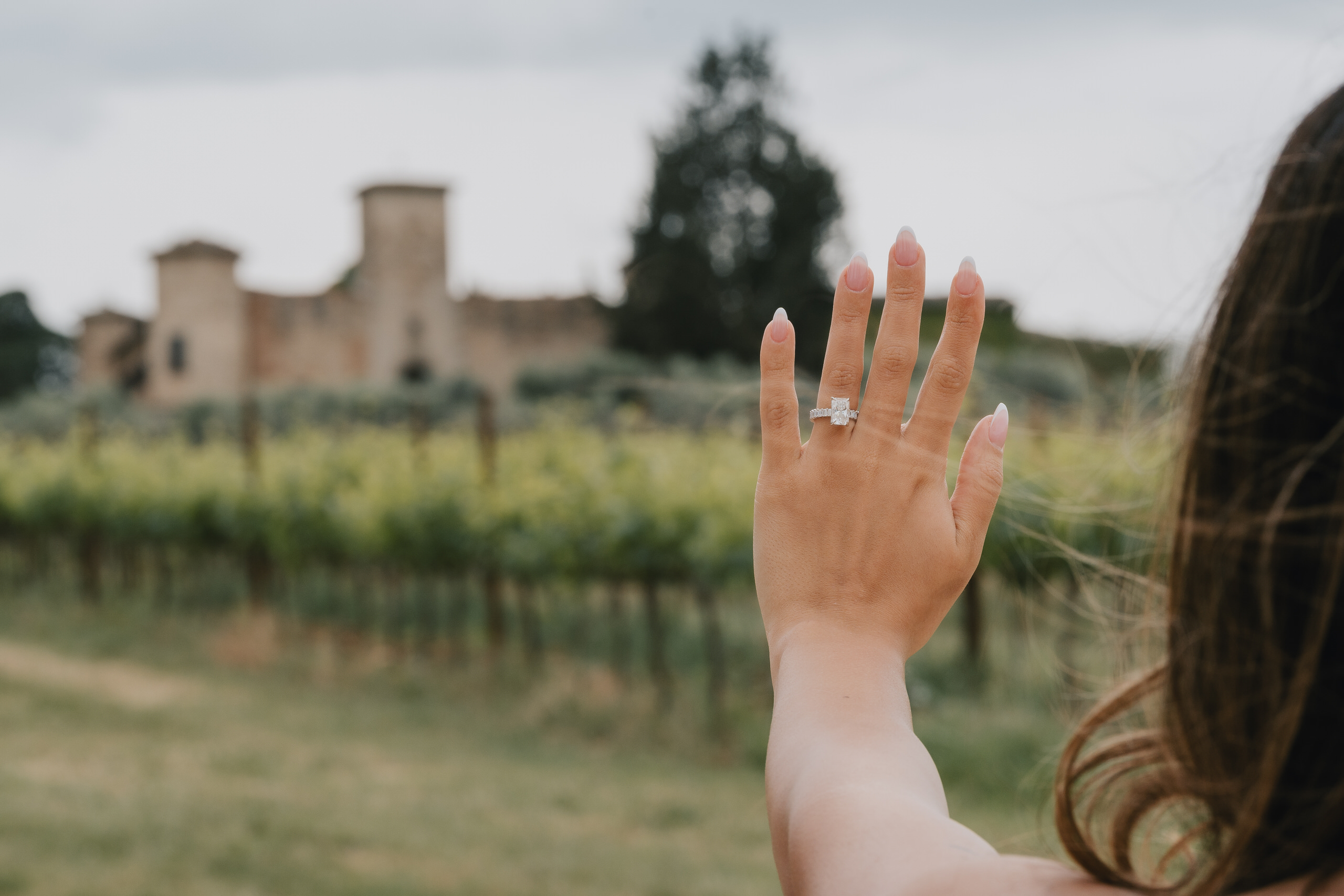 Engagement ring shown against the vineyards and the castle of Gabbiano, Chianti