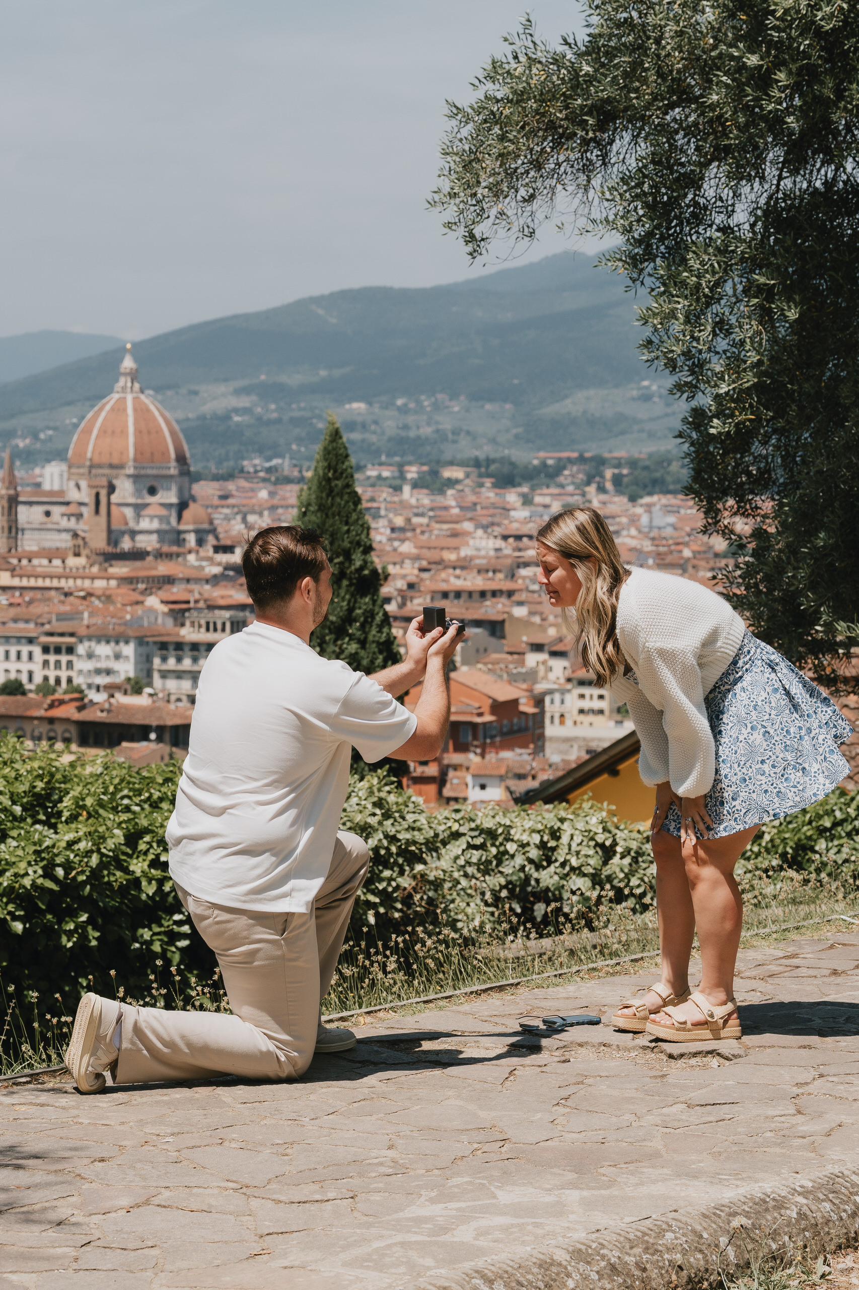 He kneels with the ring on a hillside terrace, the Duomo of Florence in the distance