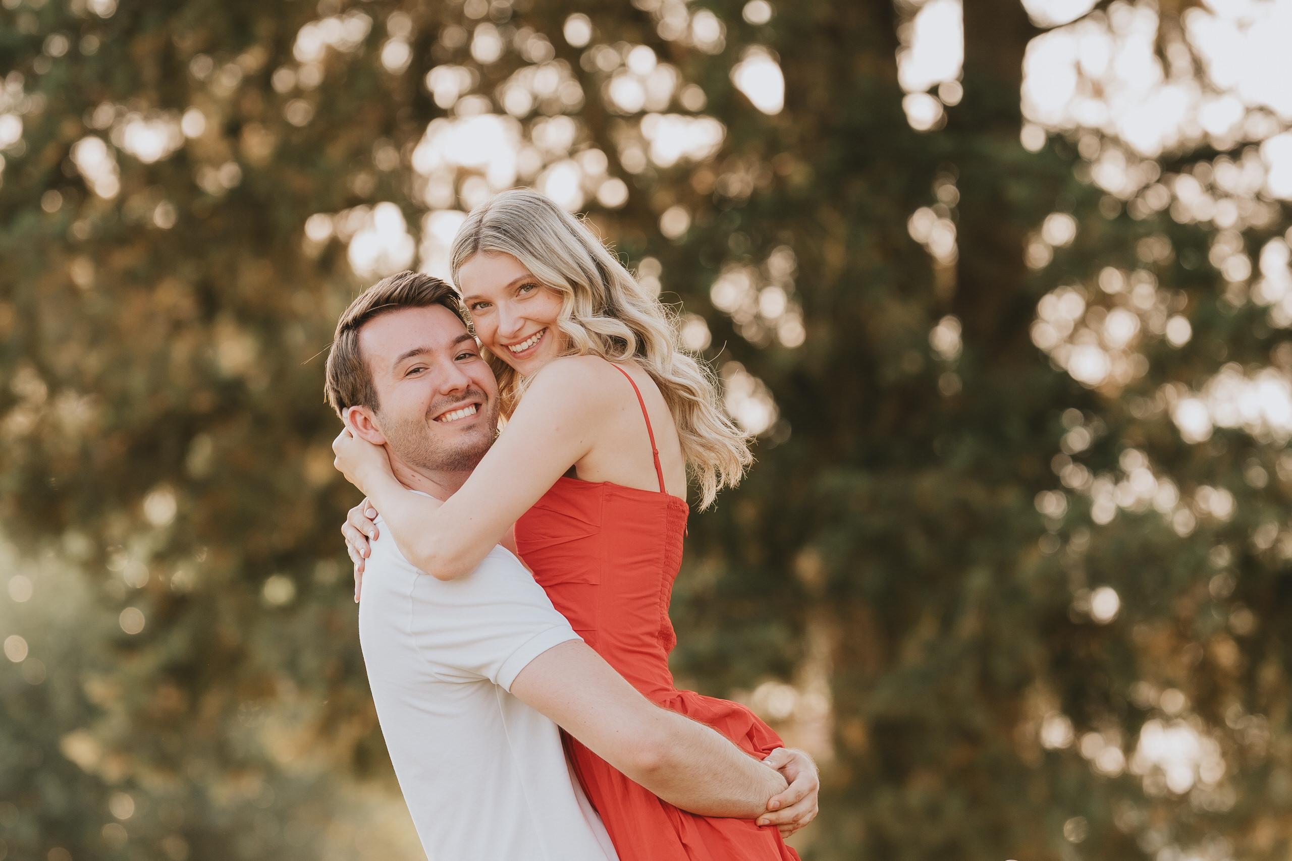 Couple hugging among trees in warm evening light after a proposal in Florence