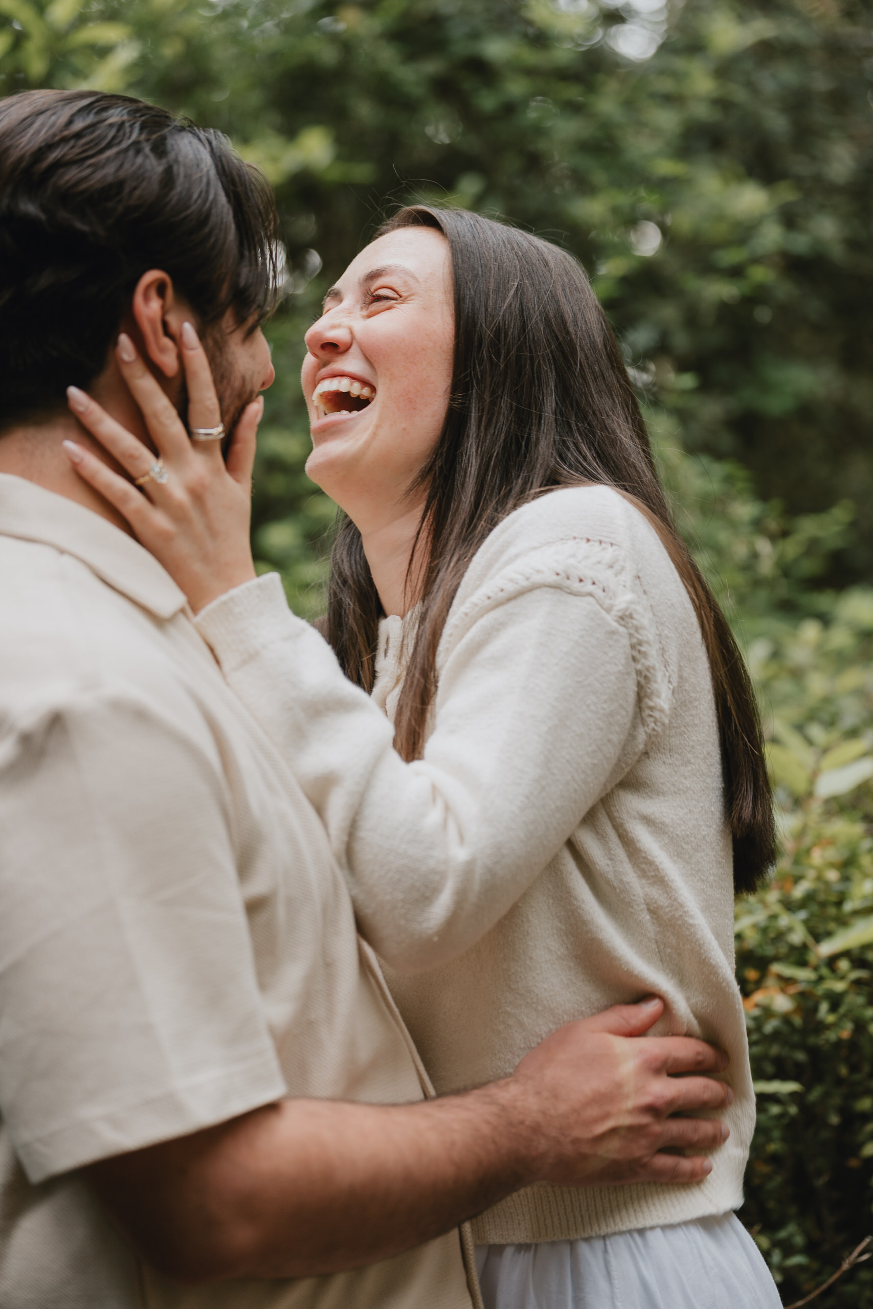 Laughing couple embracing in the greenery after a proposal in Florence