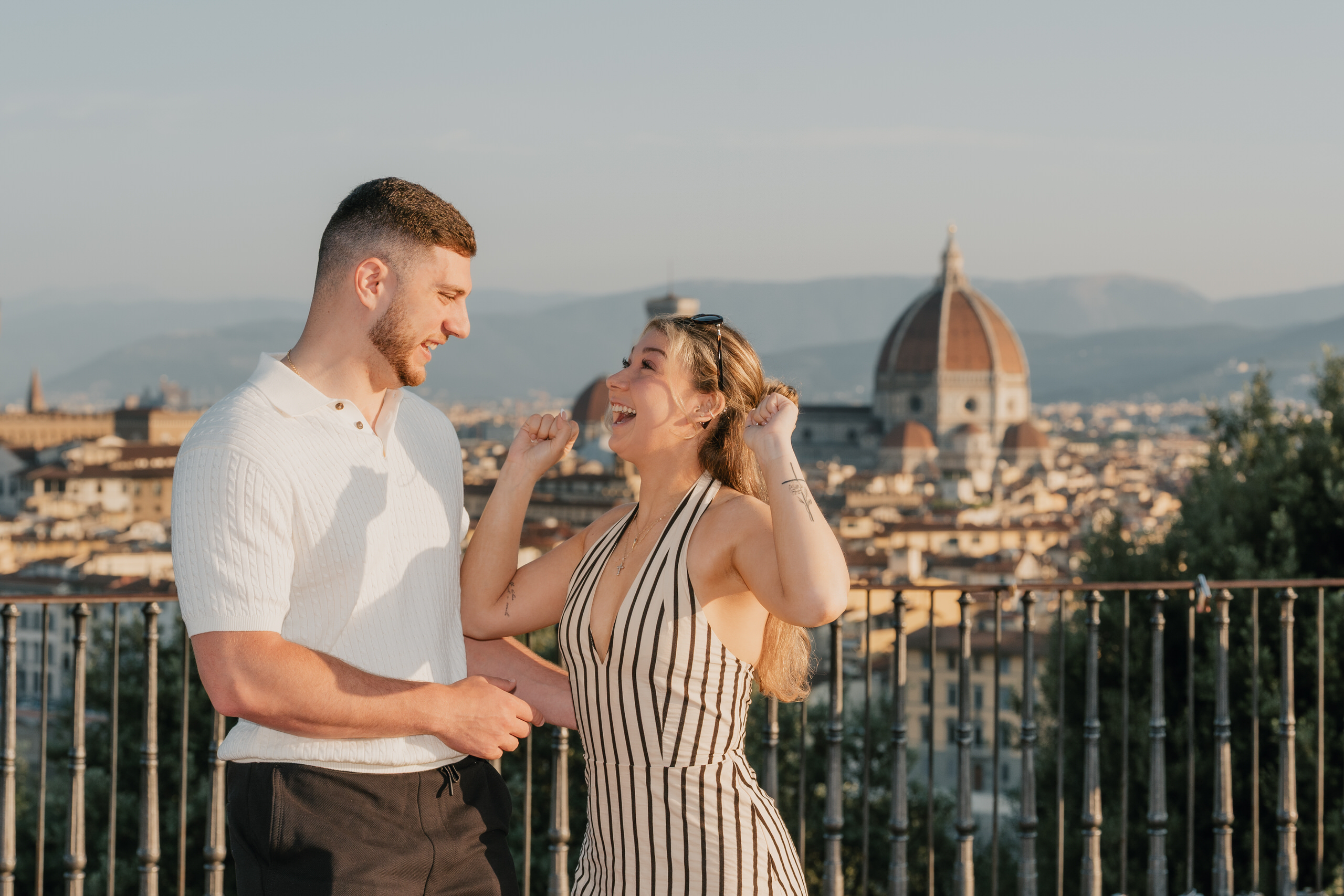 She laughs with her hands to her face, the Duomo of Florence behind