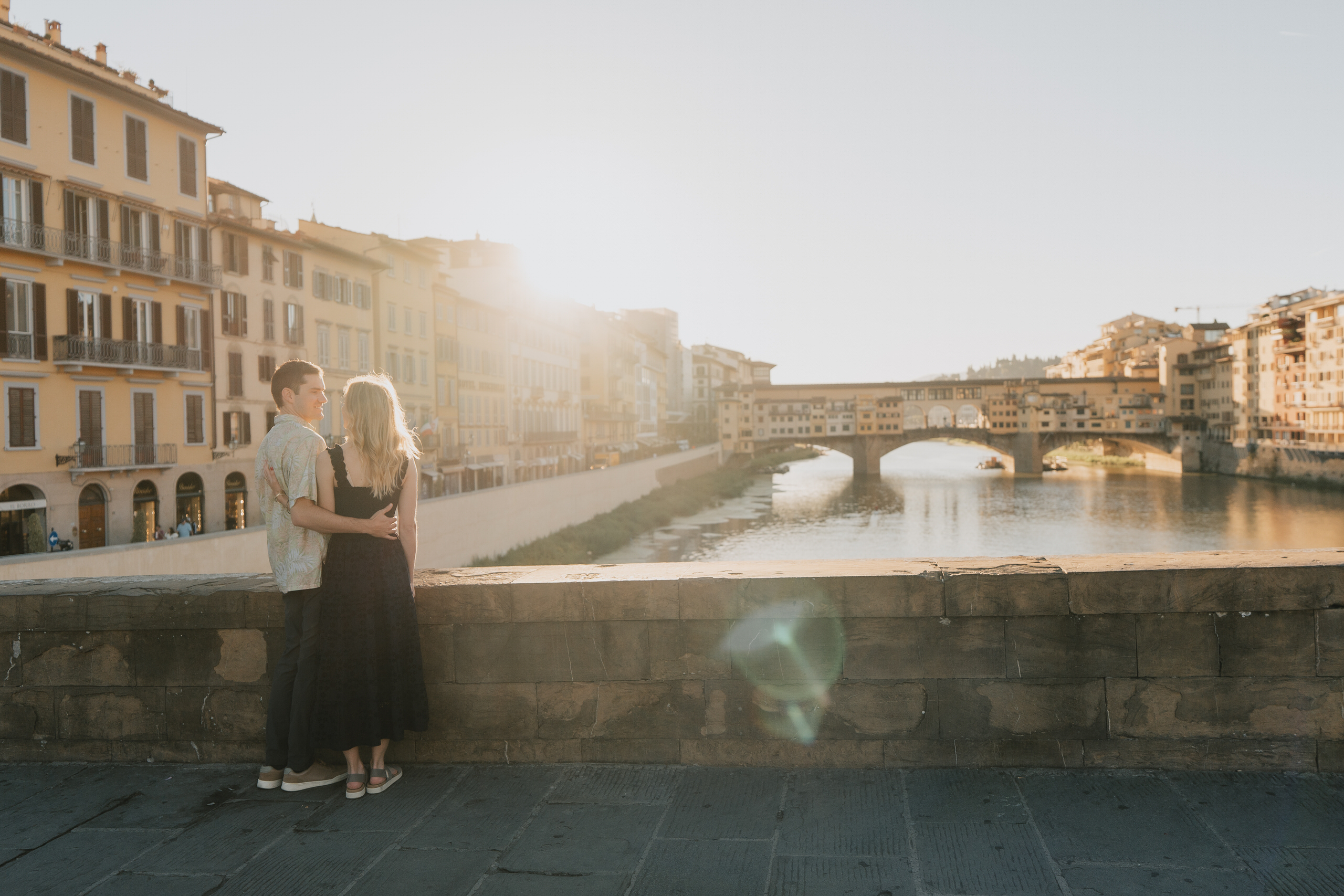 Couple by the Arno with Ponte Vecchio behind in the evening light, Florence