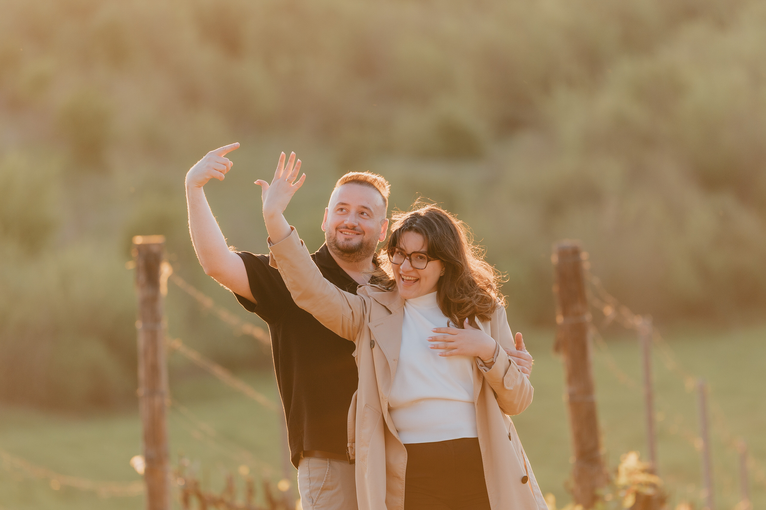 Couple waving and laughing among the vines after the proposal at Poggio Borgoni