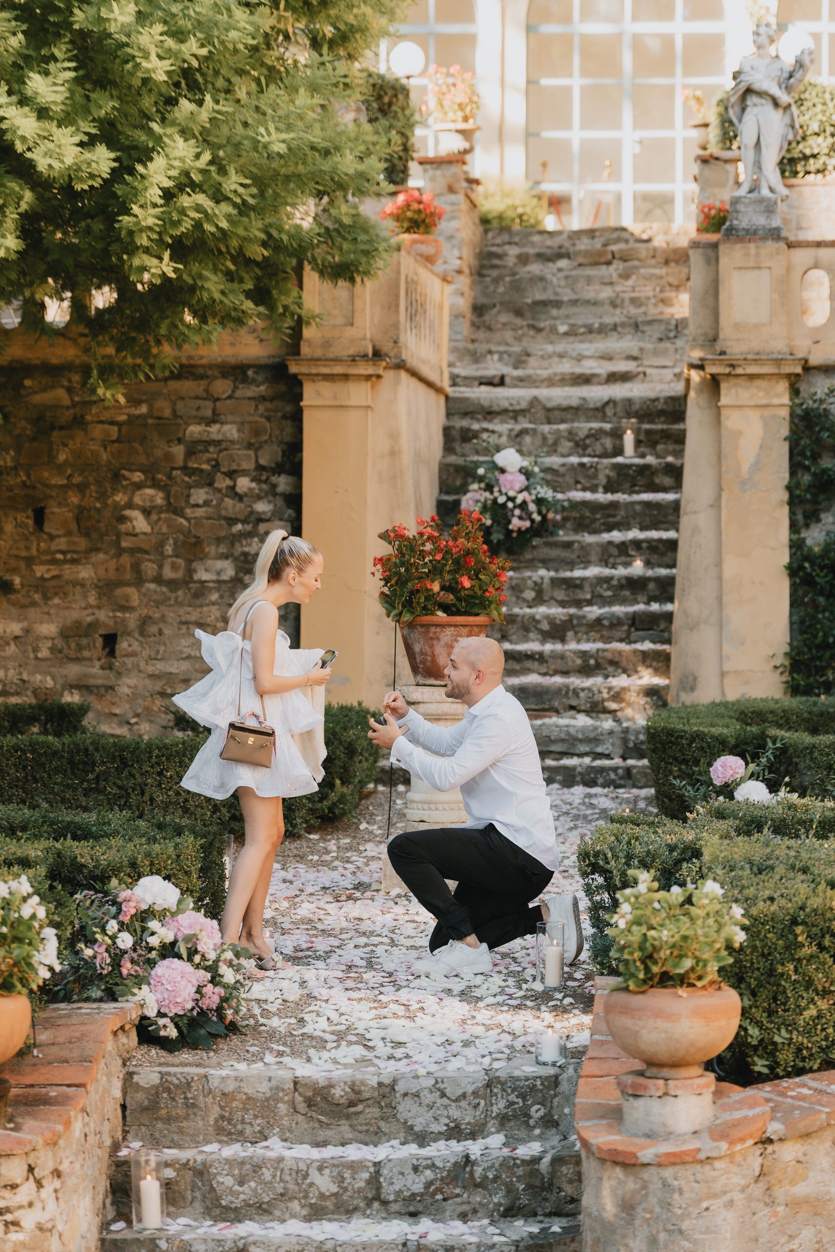 He kneels on the garden stairs of Villa Agape in Florence, petals on the steps