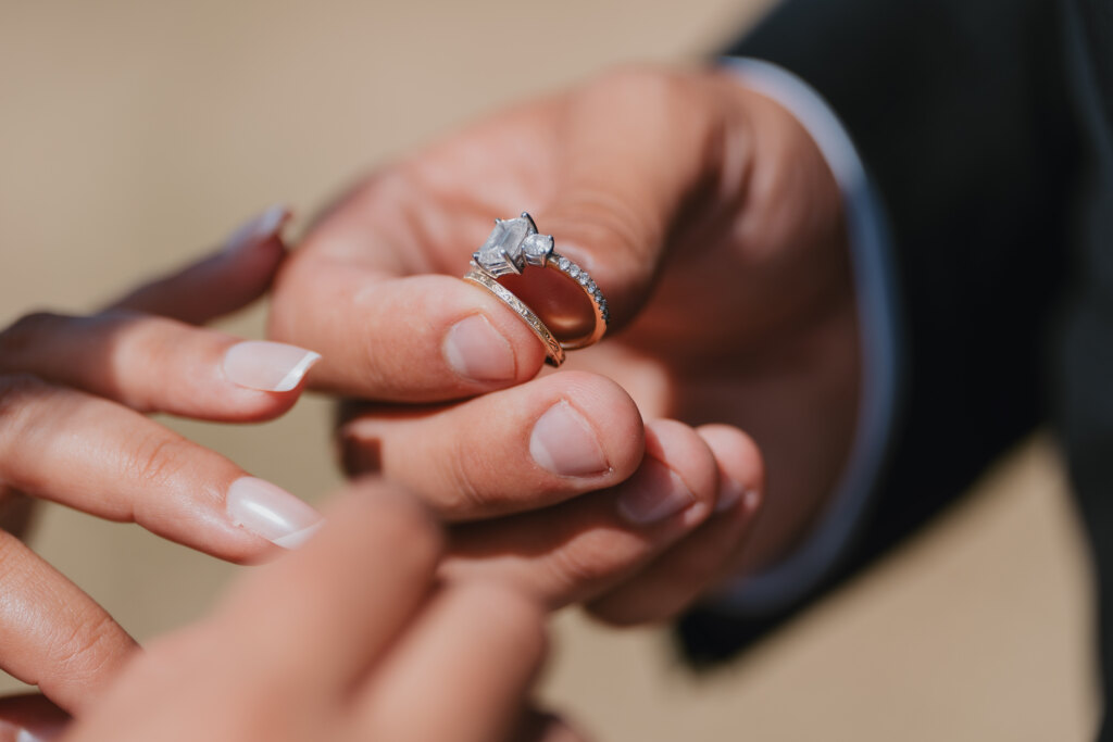 Groom holding the engagement ring and wedding band during the ceremony