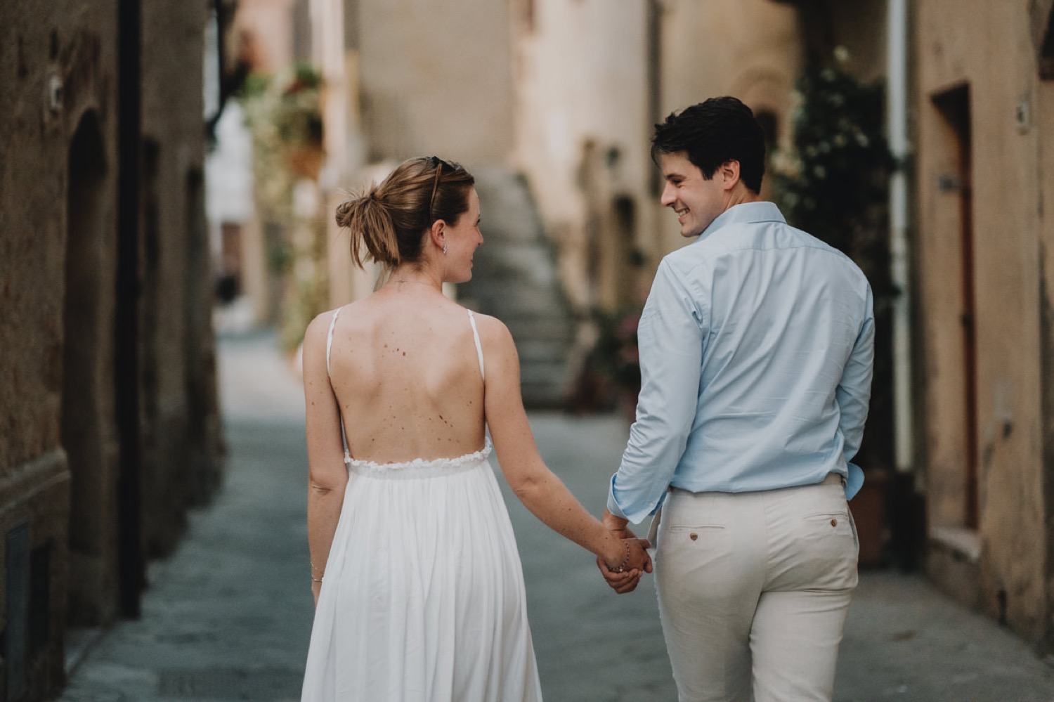 Couple seen from behind walking down a narrow street in Pienza