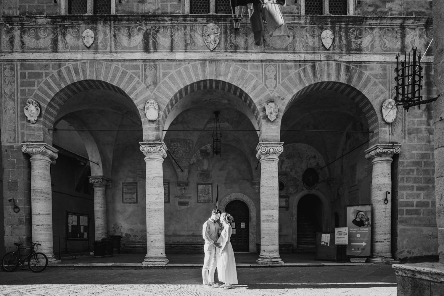 Couple under a stone loggia in Pienza, black and white