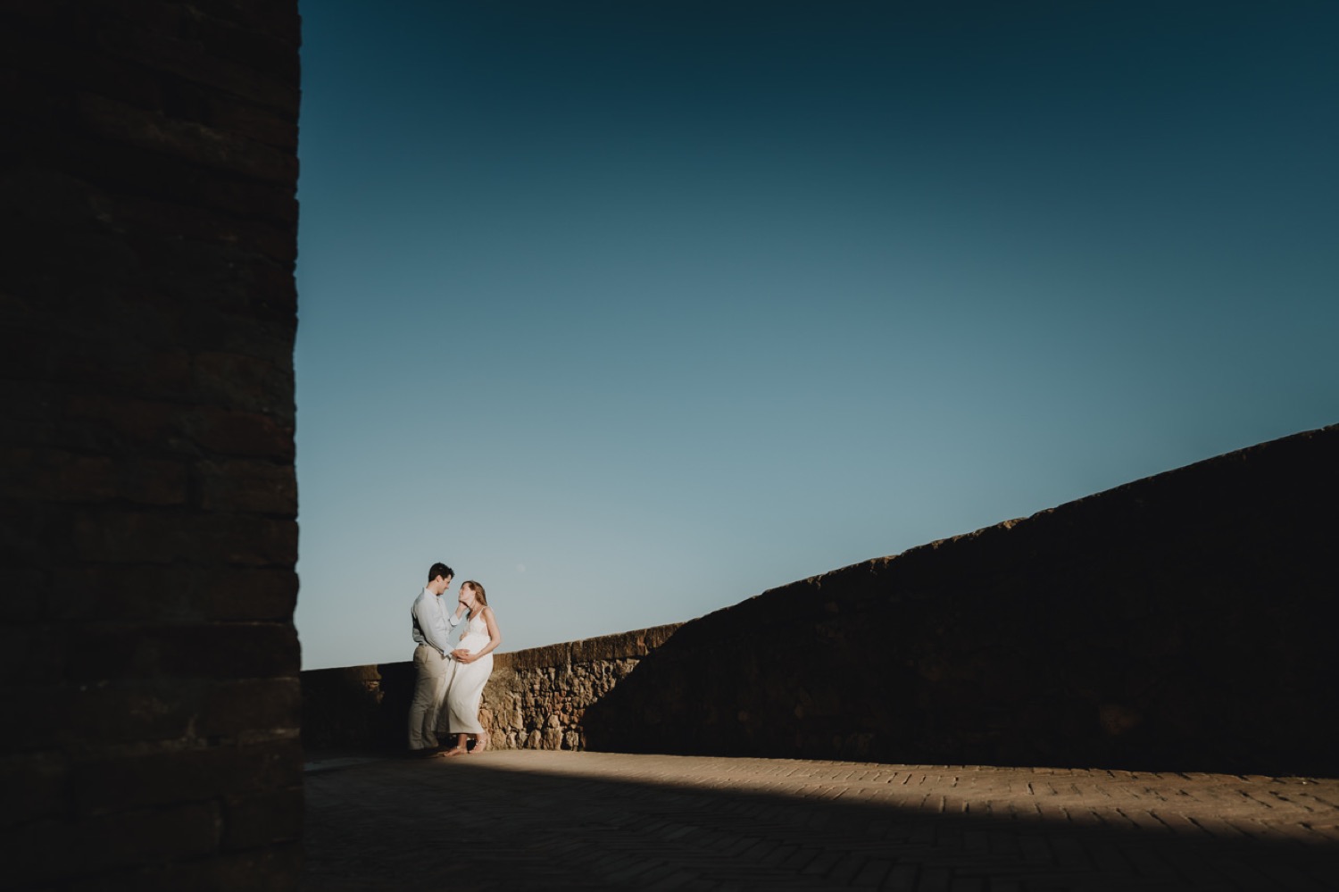 Couple silhouetted at the end of a shaded street in Pienza