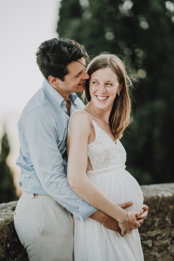 Partner embracing the mother-to-be among the cypresses