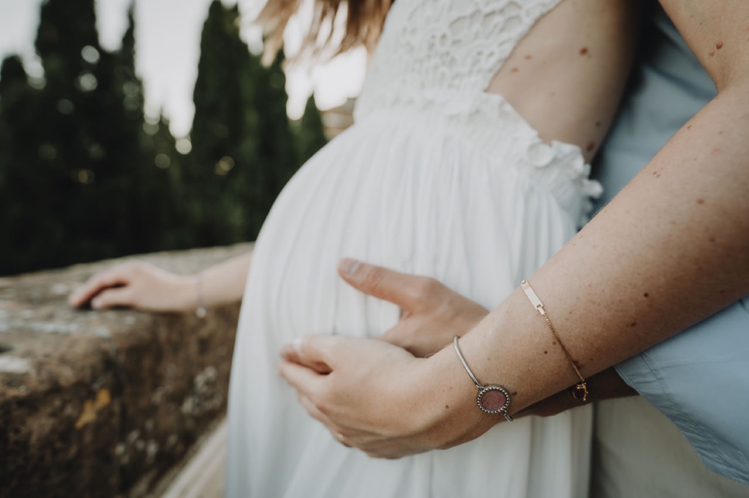 Hands on the baby bump, white dress in the Tuscan light