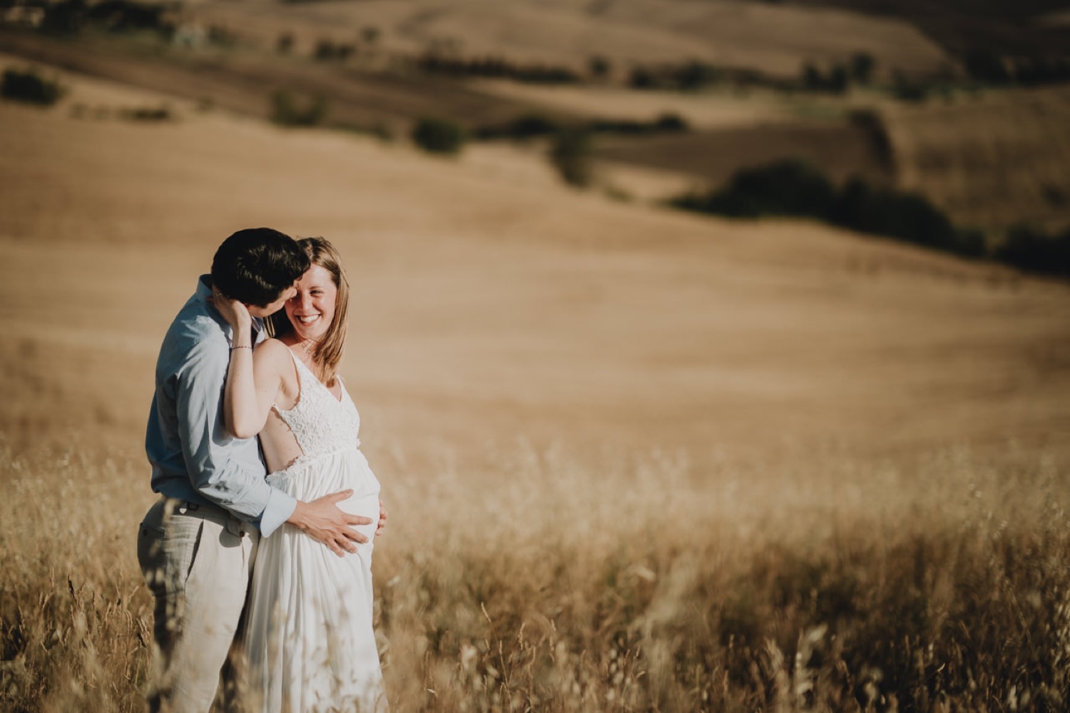 Expecting couple in the golden grass of the Val d'Orcia