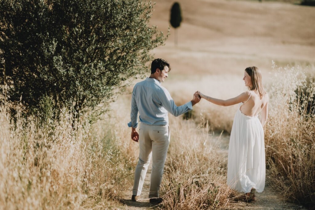 Partner leading the mother-to-be through the tall grass