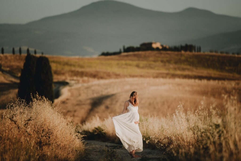 Babymoon photoshoot in Pienza: expecting couple embracing above the Val d’Orcia