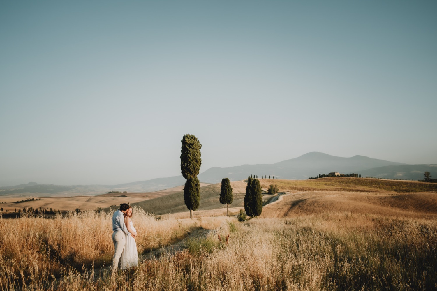Couple far away in the fields with cypresses