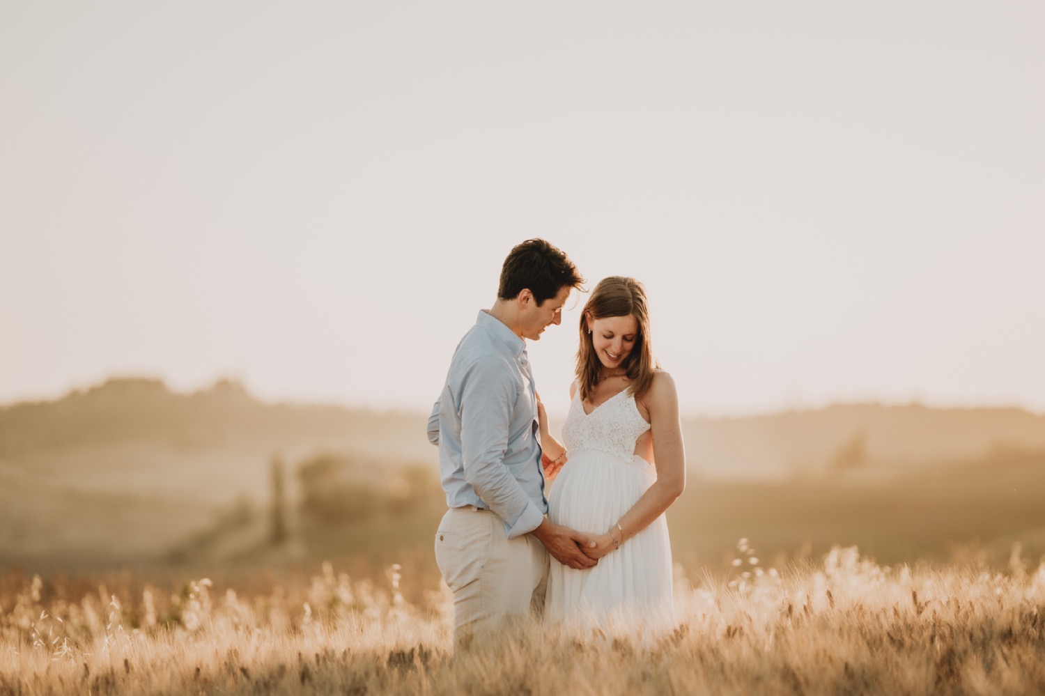 Partner kissing the mother-to-be at golden hour