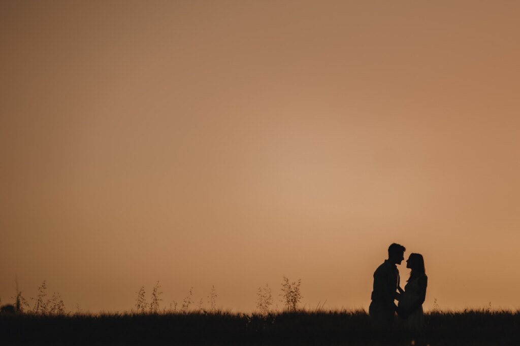 Couple silhouetted against the sunset sky over the Val d'Orcia