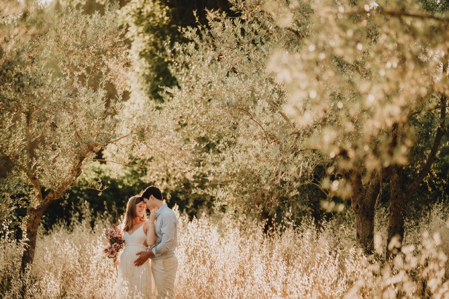 Couple sitting in the golden grass at sunset