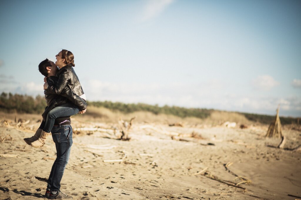 Beach couple photoshoot in Tuscany: he lifts her up
