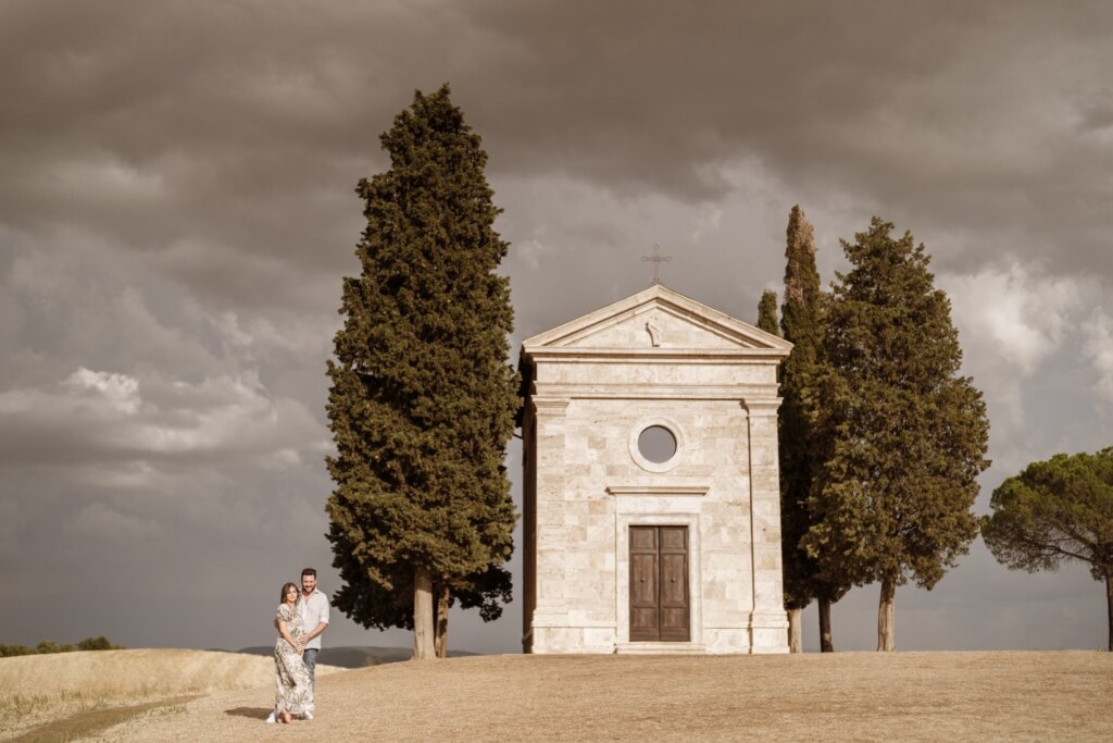 La Cappella di Vitaleta tra i cipressi, con la coppia in attesa ai suoi piedi