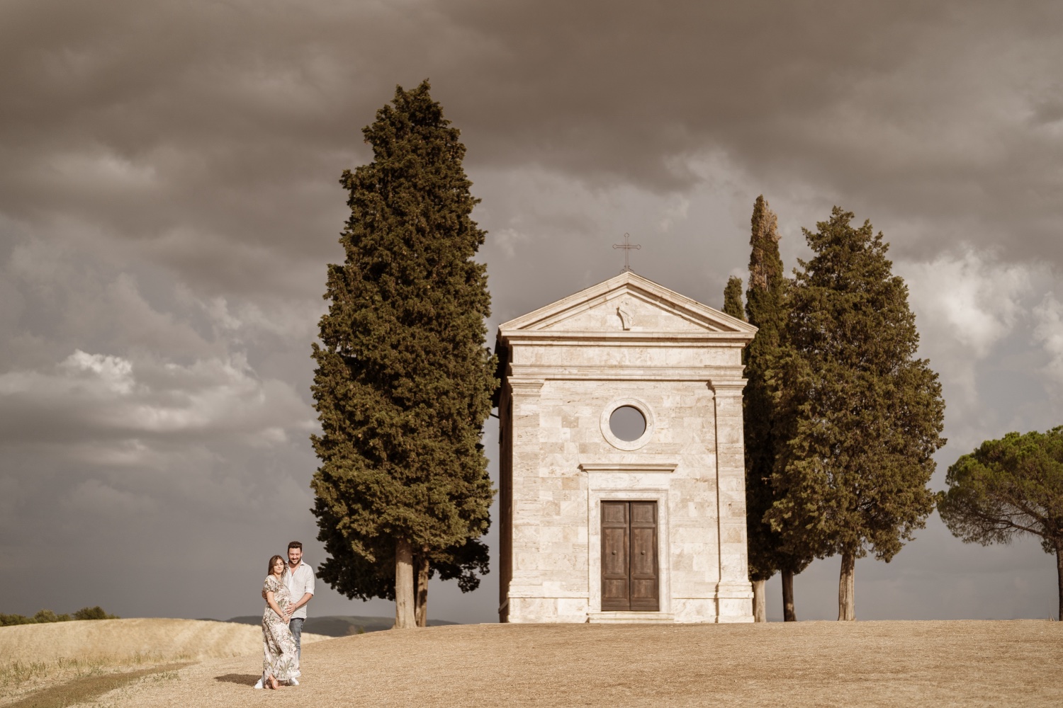 La Cappella di Vitaleta tra i cipressi, con la coppia in attesa ai suoi piedi