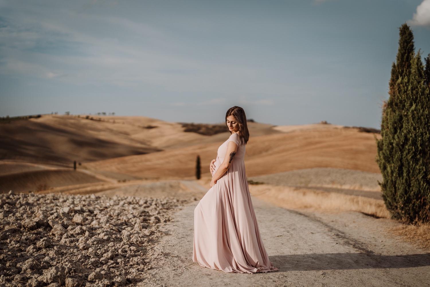 Futura mamma in abito rosa su una strada bianca