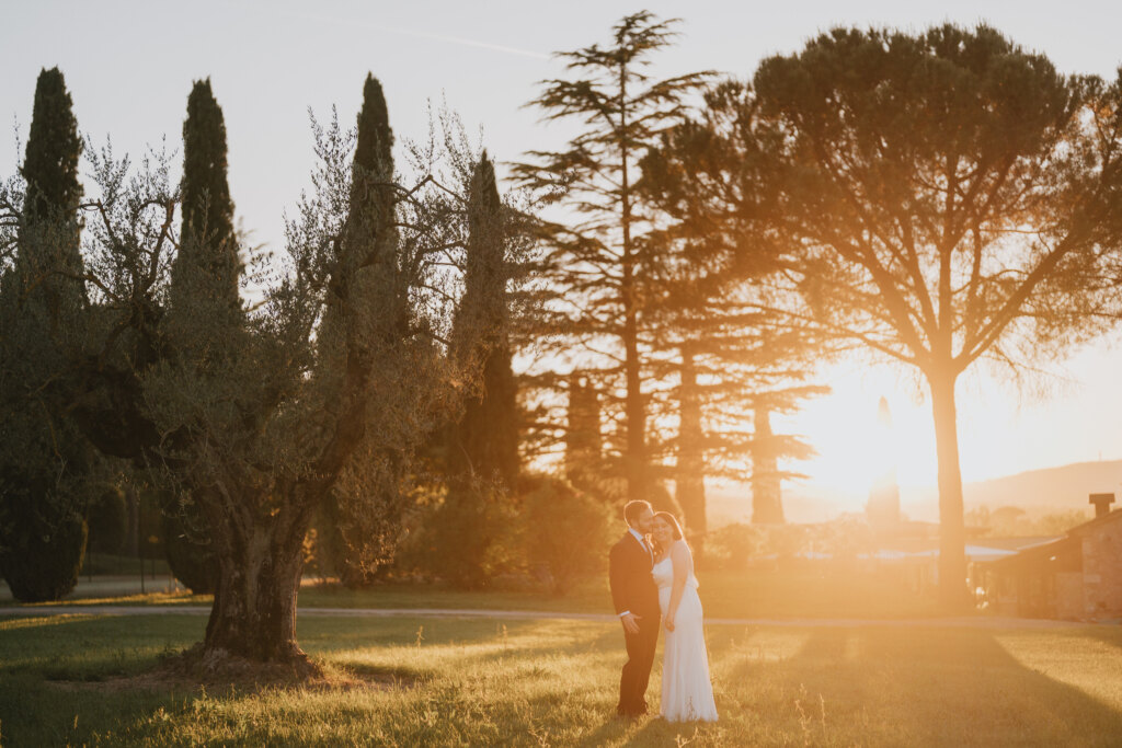 Couple embracing at sunset among cypresses, pines and olive trees